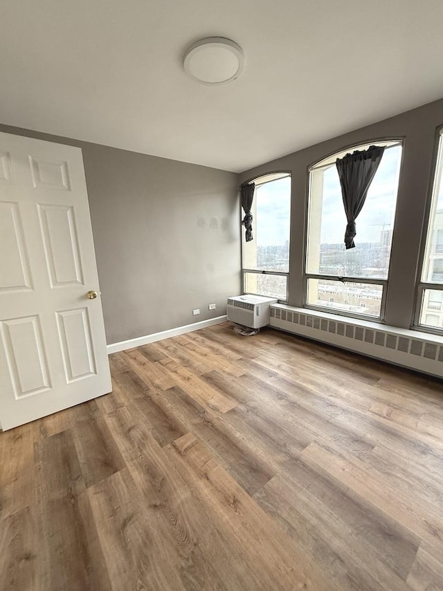 spare room with baseboard heating, baseboards, and wood finished floors