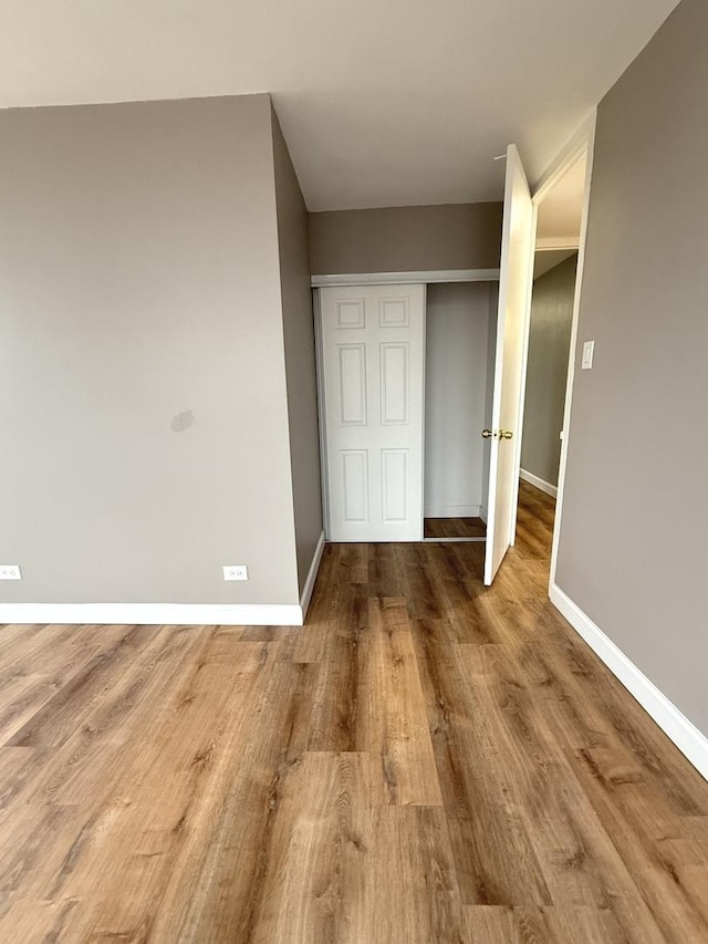 unfurnished bedroom featuring a closet, baseboards, and wood finished floors