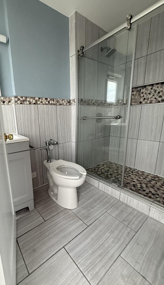 bathroom featuring vanity, tile walls, a shower stall, and toilet