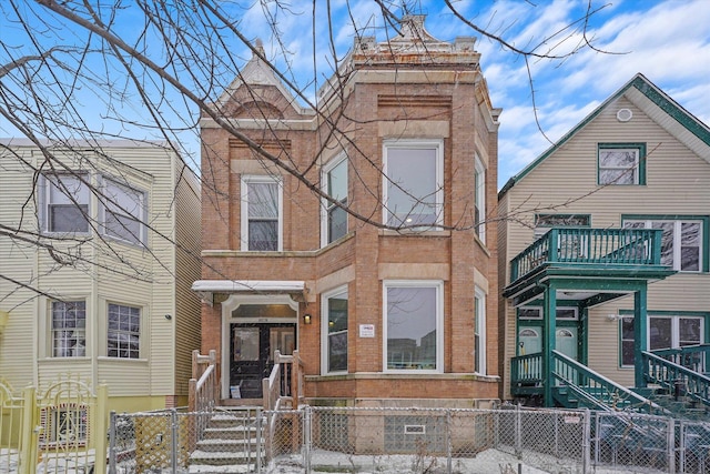 view of front of home with a fenced front yard, a balcony, brick siding, and a gate