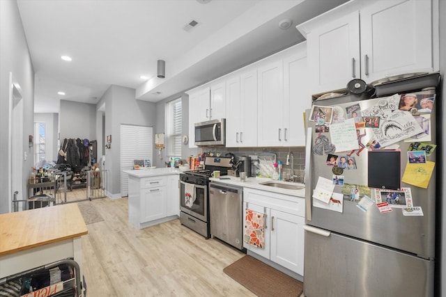 kitchen featuring visible vents, light countertops, light wood-style flooring, appliances with stainless steel finishes, and a sink