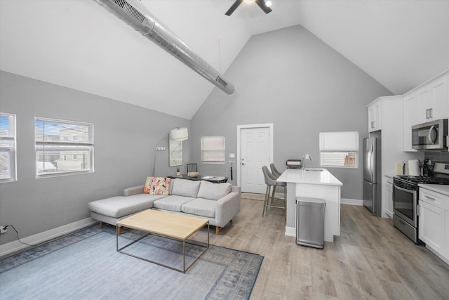 living room with high vaulted ceiling, baseboards, light wood-type flooring, and ceiling fan