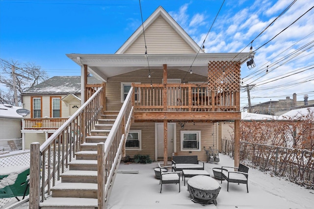 snow covered house with outdoor lounge area, a patio, stairway, and fence