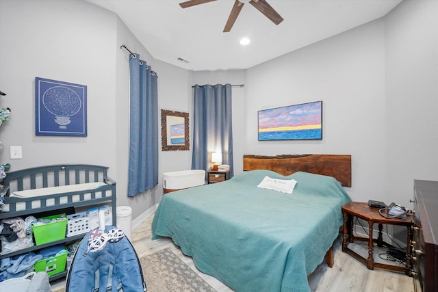 bedroom featuring light wood finished floors, visible vents, baseboards, and ceiling fan