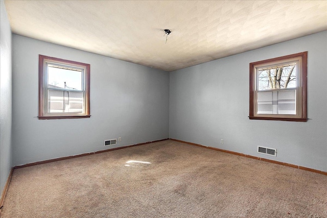 spare room with visible vents, carpet flooring, a textured ceiling, and baseboards