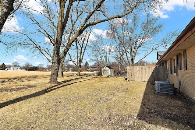 view of yard featuring a shed, central AC unit, an outdoor structure, and fence