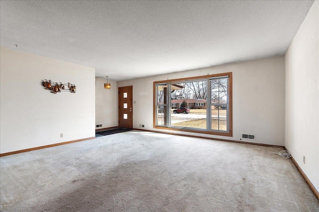 carpeted spare room featuring visible vents, baseboards, and a textured ceiling