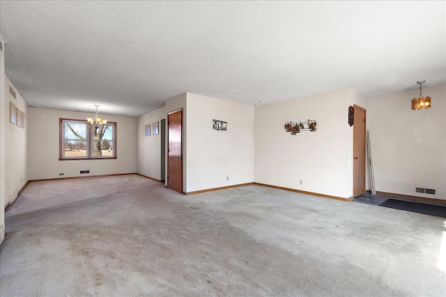 unfurnished room featuring visible vents, light colored carpet, an inviting chandelier, and a textured ceiling