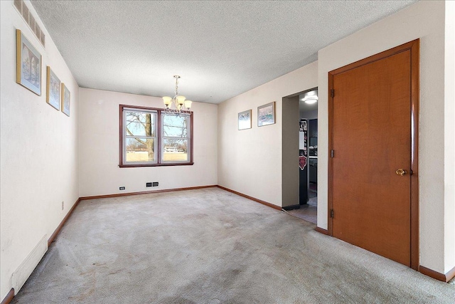 empty room featuring baseboards, visible vents, an inviting chandelier, a textured ceiling, and light carpet