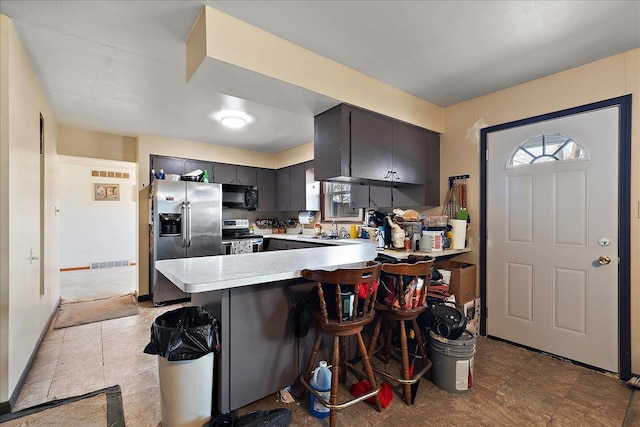 kitchen featuring visible vents, light countertops, appliances with stainless steel finishes, a peninsula, and a sink