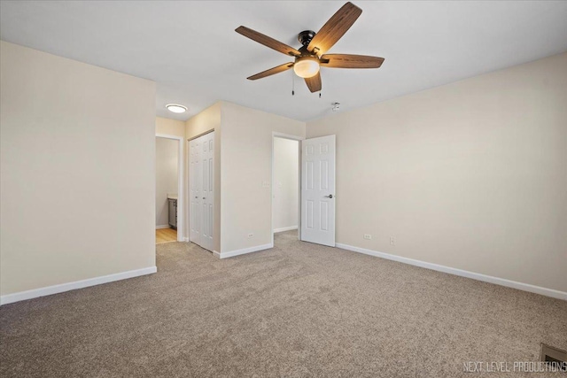 carpeted spare room featuring a ceiling fan, visible vents, and baseboards