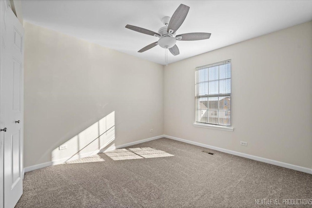 carpeted empty room with visible vents, a ceiling fan, and baseboards