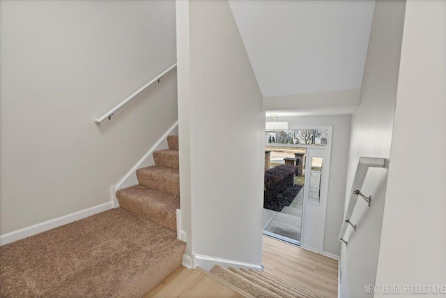 stairway with lofted ceiling, wood finished floors, and baseboards