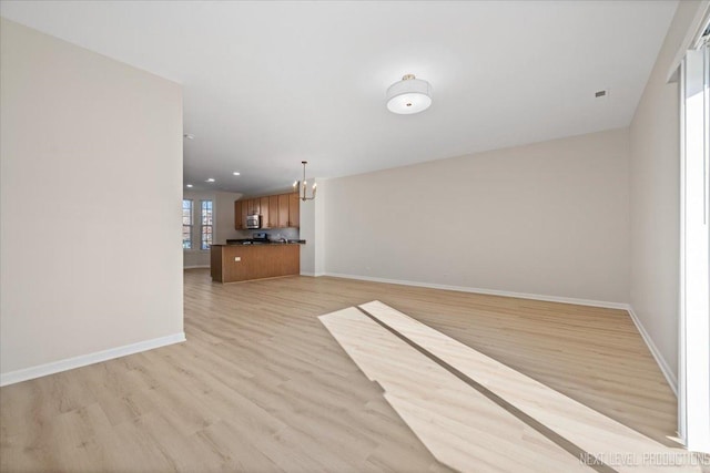 unfurnished living room featuring recessed lighting, baseboards, an inviting chandelier, and light wood-style flooring