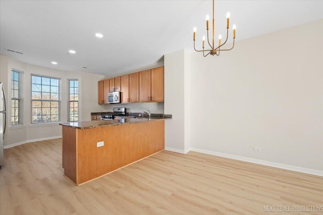 kitchen featuring dark stone countertops, baseboards, light wood-style floors, and appliances with stainless steel finishes