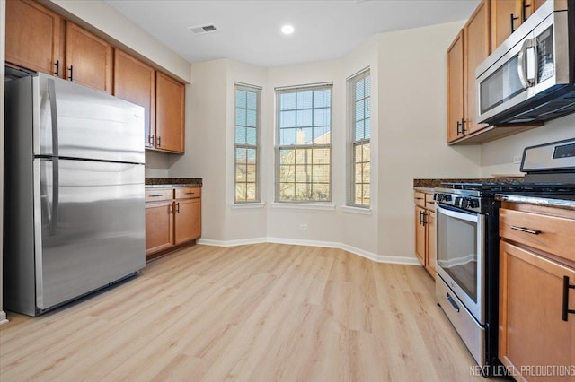 kitchen featuring visible vents, brown cabinets, appliances with stainless steel finishes, light wood finished floors, and baseboards