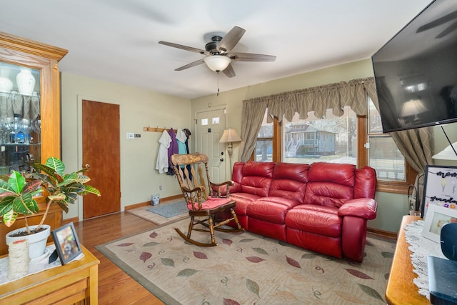 living area with a ceiling fan, wood finished floors, and baseboards