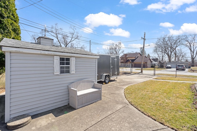 exterior space featuring an outbuilding, fence, a lawn, and roof with shingles