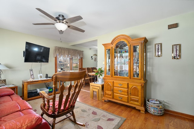 living room with wood finished floors, baseboards, and ceiling fan