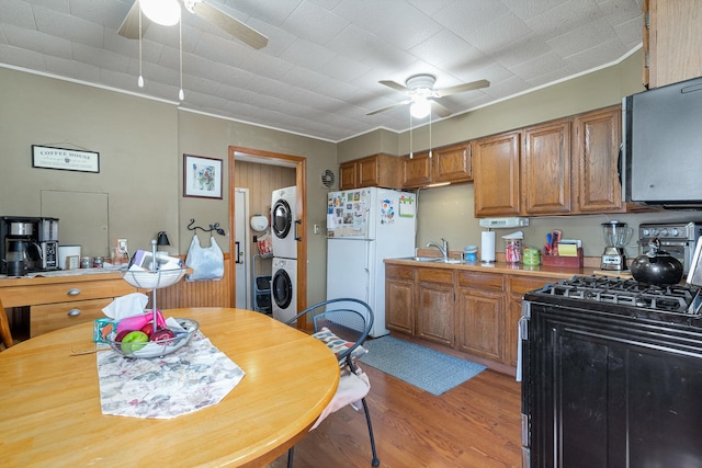 kitchen with black gas range oven, stacked washer / dryer, stainless steel microwave, ceiling fan, and freestanding refrigerator