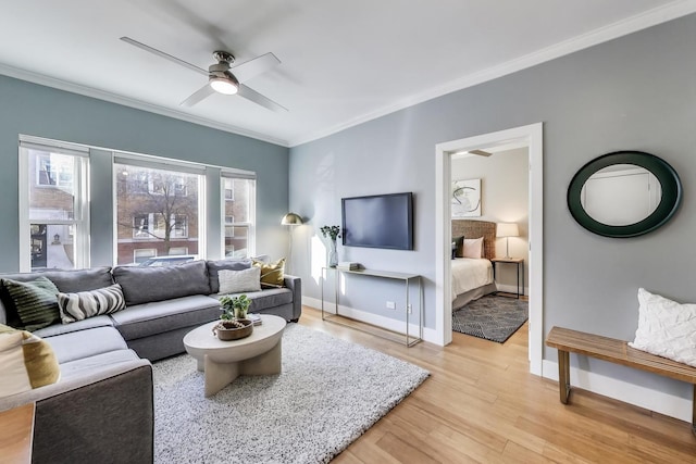 living room featuring crown molding, light wood-style floors, baseboards, and ceiling fan