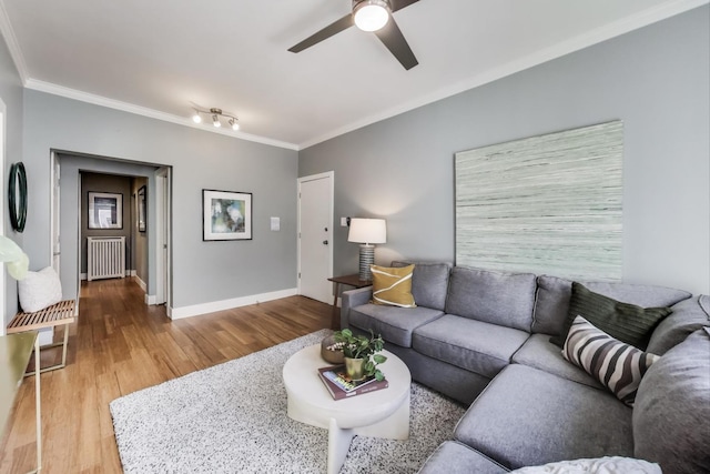 living area featuring radiator, crown molding, baseboards, and wood finished floors