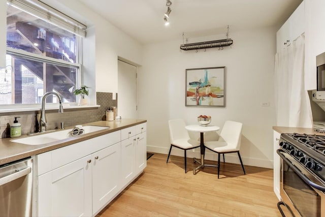 kitchen featuring tasteful backsplash, stainless steel appliances, light wood finished floors, and a sink