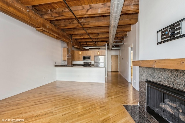 unfurnished living room featuring wood finished floors, wooden ceiling, a fireplace, beamed ceiling, and baseboards