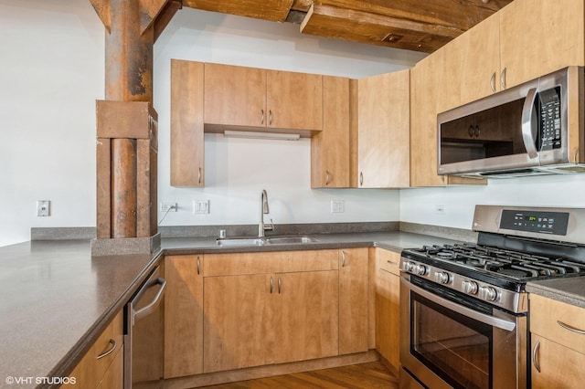 kitchen with a sink, dark countertops, and appliances with stainless steel finishes