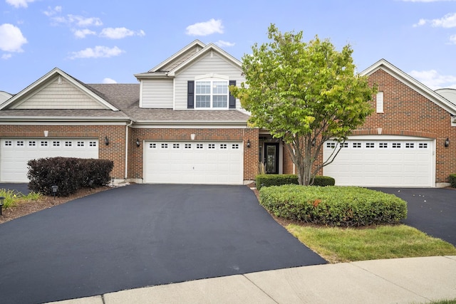 view of front of home featuring aphalt driveway, brick siding, and roof with shingles