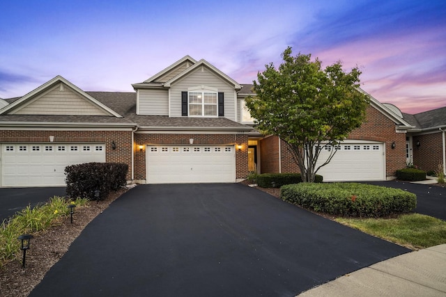 view of front of property with brick siding, driveway, a shingled roof, and a garage