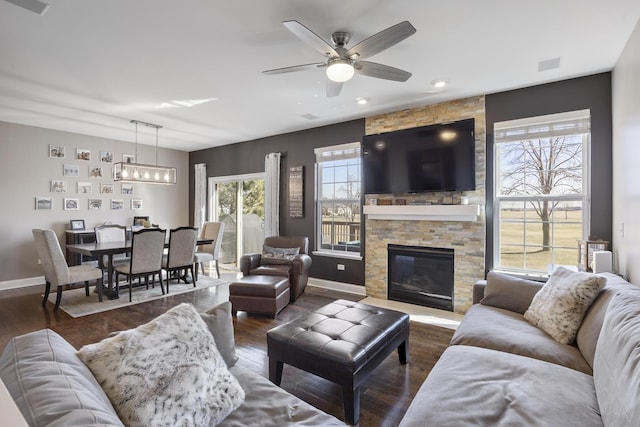 living area featuring dark wood finished floors, visible vents, a stone fireplace, and baseboards