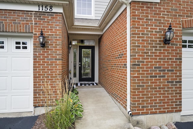 entrance to property with a garage and brick siding