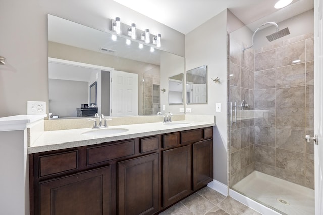 ensuite bathroom with double vanity, visible vents, a shower stall, and a sink