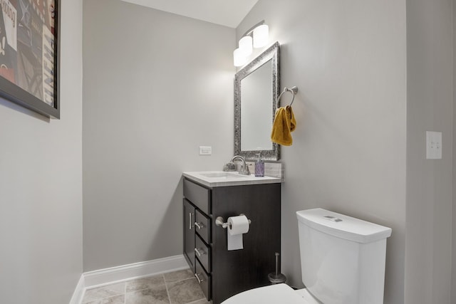 half bath featuring vanity, toilet, and baseboards