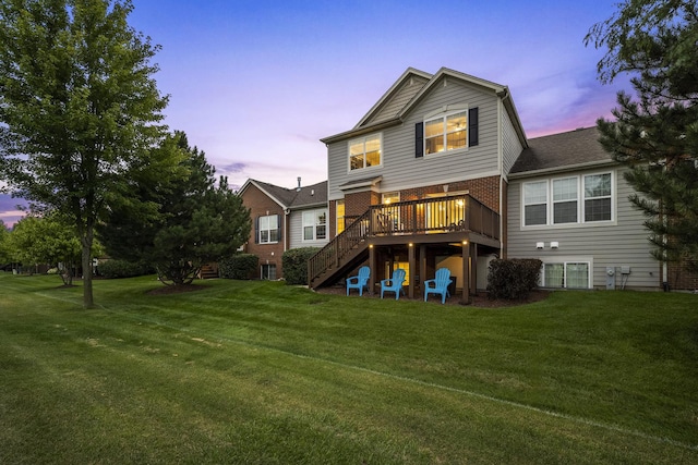 back of house at dusk with stairway, a lawn, brick siding, and a wooden deck