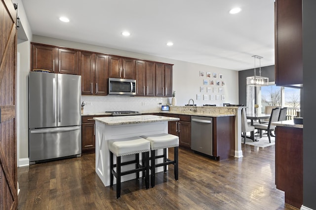 kitchen with dark wood-style floors, backsplash, appliances with stainless steel finishes, and a peninsula