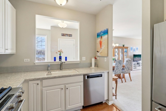 kitchen with white cabinetry, light stone countertops, appliances with stainless steel finishes, and a sink