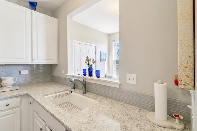 kitchen featuring decorative backsplash, white cabinetry, and a sink