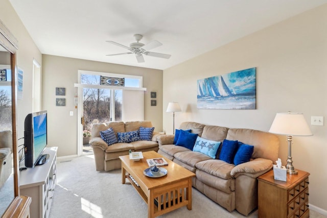 living area with a ceiling fan, light colored carpet, and baseboards