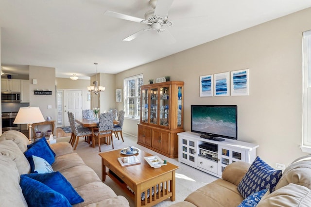 living room featuring light carpet and ceiling fan with notable chandelier