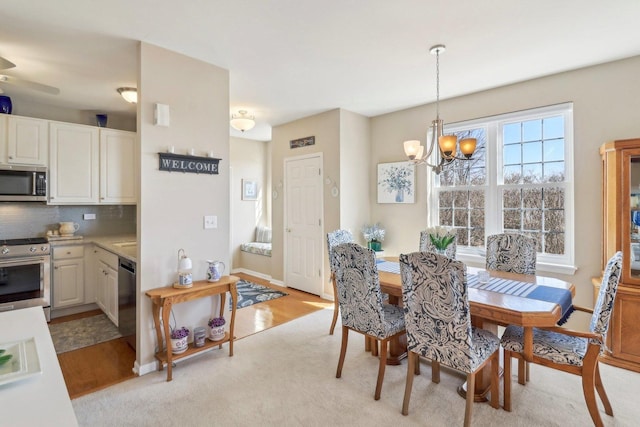 dining area with baseboards, a notable chandelier, and light wood finished floors