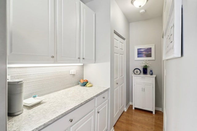 kitchen featuring white cabinetry, wood finished floors, tasteful backsplash, and baseboards