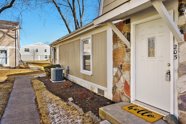 doorway to property featuring central air condition unit and stone siding