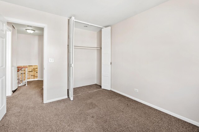 unfurnished bedroom featuring baseboards, carpet floors, and a closet