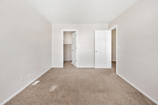 unfurnished bedroom featuring baseboards, visible vents, carpet floors, a closet, and a walk in closet