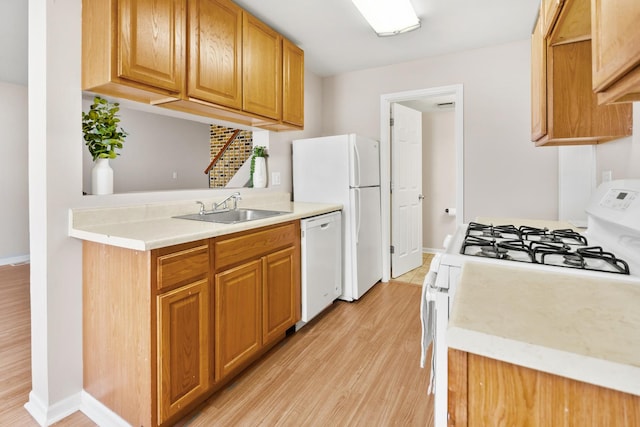 kitchen featuring white appliances, baseboards, light wood-style flooring, a sink, and light countertops