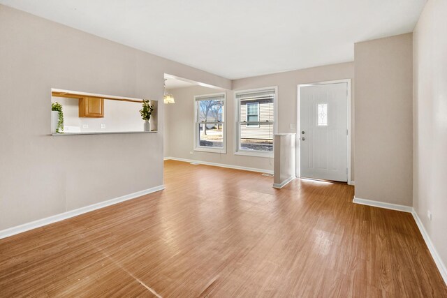 entryway with baseboards, a notable chandelier, and wood finished floors