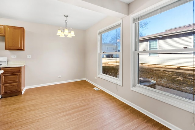 unfurnished dining area featuring visible vents, light wood-style floors, baseboards, and a chandelier