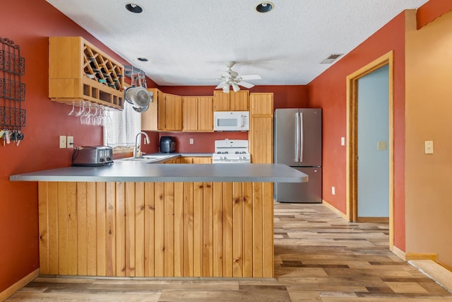 kitchen with white appliances, light wood-style floors, visible vents, and a sink